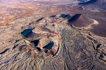 Drone shot of an extinct volcano crater and the lava fields of the Berserkjahraun region, Snaefellsnes Peninsula, Iceland. A dirt road can be seen winding through the area.
