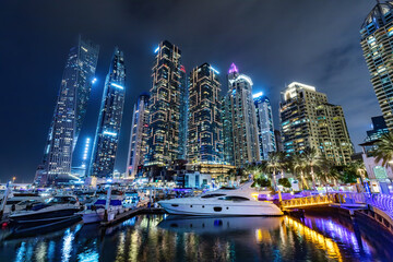 Marina with yachts and skyscrapers in Dubai UAE at night
