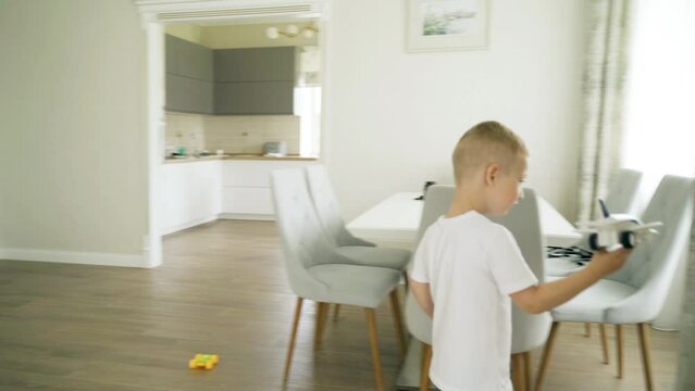 The boy is playing with a toy plane, running around the room. Children's games
