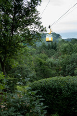 A pendulum cable car over a mountain forest.