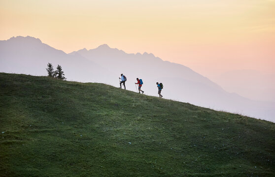 Hikers with hiking poles on mountain at sunrise, Mutters, Tyrol, Austria