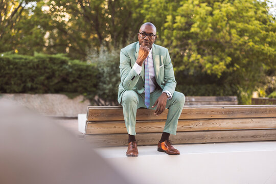 Thoughtful mature businessman sitting on bench in park