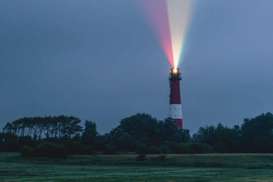 Germany, Schleswig-Holstein, Pellworm, Pellworm Lighthouse casting colorful light at dusk