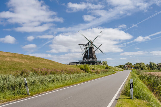 Germany, Schleswig-Holstein, Pellworm, Country road with Nordermuhle mill in background