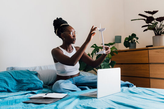 Businesswoman analyzing wind turbine model with laptop at home