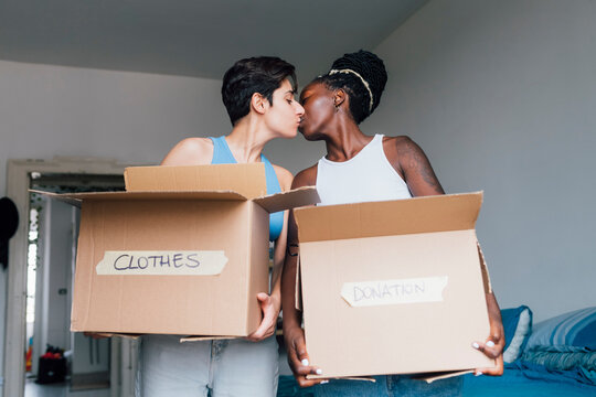 Lesbian Couple Carrying Boxes Kissing Each Other At Home