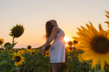 Carefree woman enjoying weekend at sunflower field on sunset