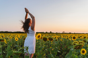 Woman practicing yoga at sunflower field on sunset