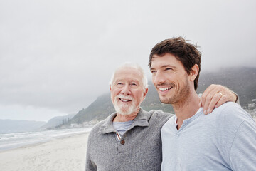 Proud father standing on the beach with his adult son