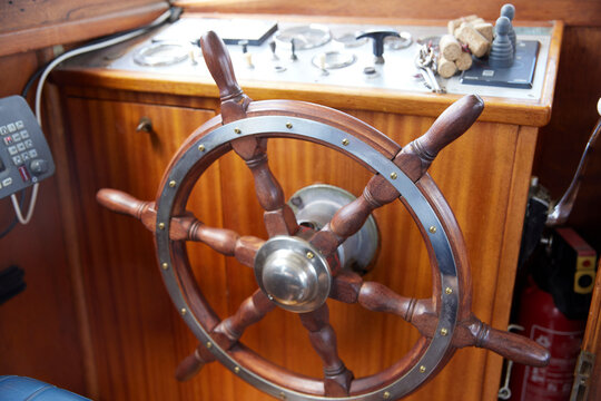 Wooden helm of motorboat on dashboard in cockpit