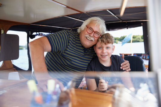 Happy grandfather embracing grandson in boat