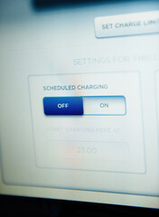 Close-up macro shot of a schedule charging button on the new electric car dashboard digital display screen