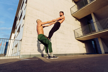 Young athletic men doing balance exercises together