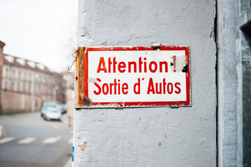 Old vintage inscription on wall building - Attention, sortie d'autos - translated as pay attention, car exits from building