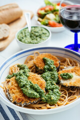 Dish with home made breaded eggplant with spinach pesto, served on spaghetti