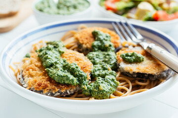 Dish with home made breaded eggplant with spinach pesto, served on spaghetti