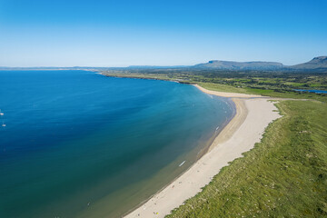 Fototapeta na wymiar Stunning sandy beach and blue ocean and sky. Aerial view. Mullaghmore town area in county Sligo, Ireland, Popular travel destination with beautiful nature scenery and water sports. Warm sunny day.