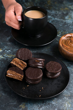 Alfajores with dulce de leche against person holding cup