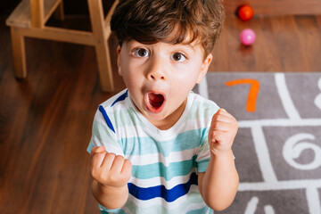 Excited toddler celebrating victory on floor