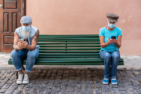Senior couple sitting on a bench maintaining social distance