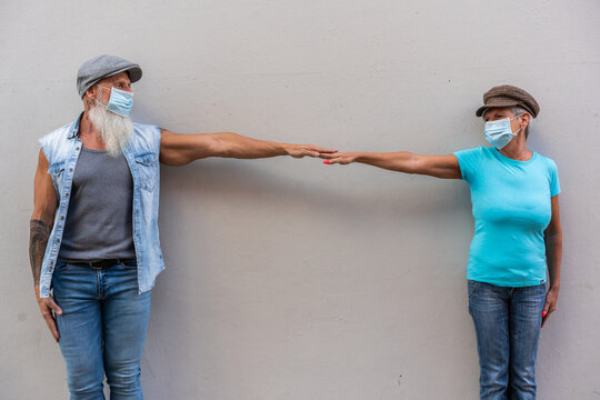 Senior couple standing by a wall maintaining social distance