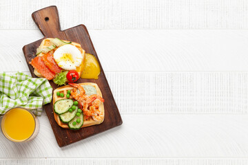 Breakfast waffles with fried eggs, salmon, cucumber and prawns