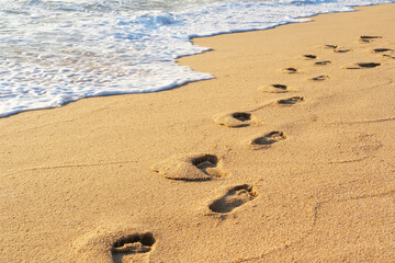 Male footprints in the sand next to the sea close-up.