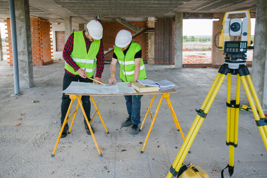 Surveyor engineer working at construction site with measuring eq