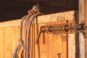 Closed door to a wooden horse stable at sunset. Halters ropes for horses. Breeding care of horses