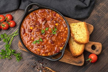 Mexican food chile con carne dish on a wooden backdrop. Bean and corn soup, red bean stew