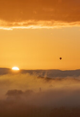 Golden sunrise with silhouette of a distant hot air balloon 