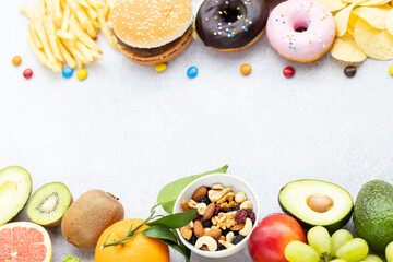Flat lay of Healthy and unhealthy food from fruits and vegetables vs fast food, sweets and pastry on gray concrete background. Diet and detox against calorie and overweight lifestyle concept.