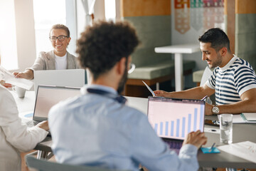 Group of young diverse coworkers analyzing sales report while working together in the office