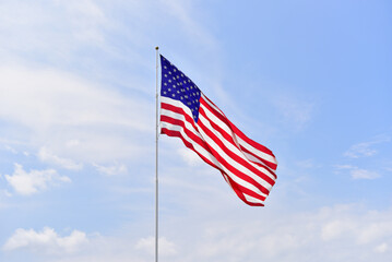United States flag waving on a blue sky with white fluffy clouds