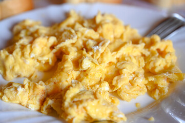 Scrambled eggs on a plate in restaurant. Eggs prepared for breakfast, close up.