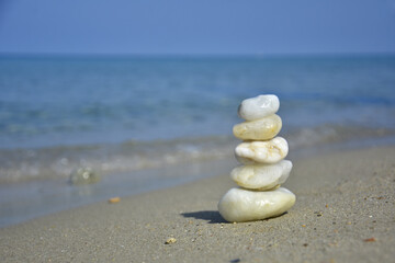 Fototapeta na wymiar Balanced stone pyramid on sand on beach. Zen rock, concept of balance and harmony
