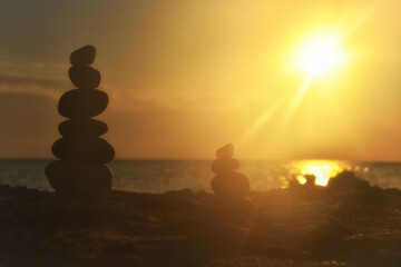Silhouette of balanced stone pyramid on sand. Zen rock, concept of balance and harmony, stone pyramid on beach