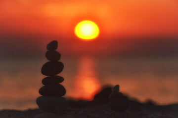 Silhouette of balanced stone pyramid on sand. Zen rock, concept of balance and harmony, stone pyramid on beach