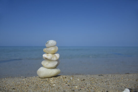 Balanced stone pyramid on sand on beach. Zen rock, concept of balance and harmony