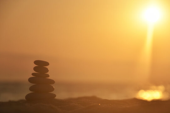 Silhouette of balanced stone pyramid on sand. Zen rock, concept of balance and harmony, stone pyramid on beach