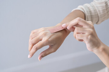Young woman opens a band-aid, female sticking adhesive plaster bandage on her hand , closeup. medicine care