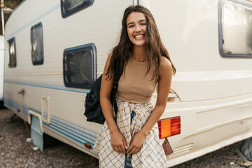 Cheerful young caucasian girl laughs broadly smiling looking at camera relaxing outdoors. Brunette...