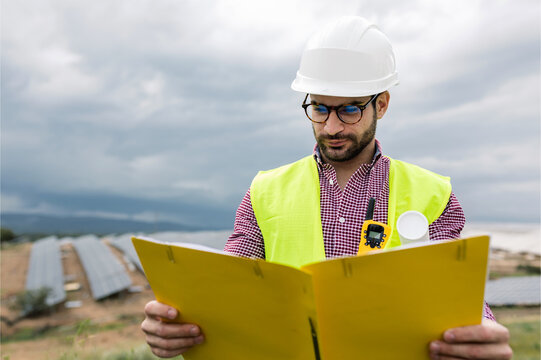 Male contractor reading documents near solar farm