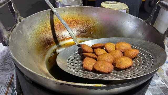 Cook frying and selling Moong Dal Pakoda, often referred to as Moong Dal Bhajiya or Moong Dal Vada, is frequently sold on the streets of Kolkata, West Bengal.