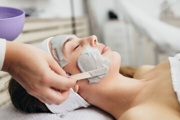 Obraz na płótnie Canvas Beautiful and attractive adult woman receiving professional facial care beauty treatment with peeling mask.