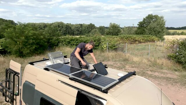 Man on the roof of a caravan working on solar power supply