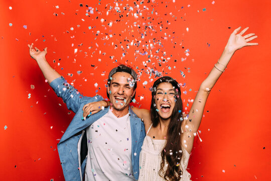 Excited Couple In Trendy Wear Under Confetti During Festive Event