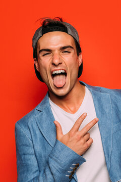 Stylish man with tongue out on red background