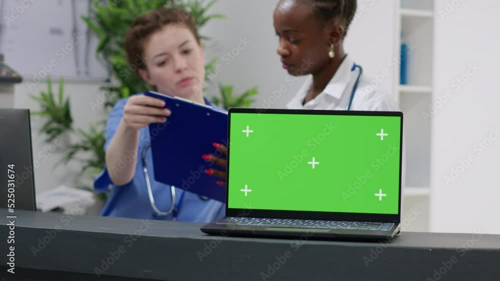 Poster laptop with greenscreen display on hospital reception counter used by medical team. working with bla