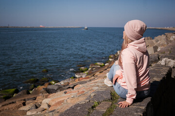 a blonde girl on the background of a cold sea, seagulls in the sky. travel and travel concept, immigration. girl pouring at the beach, casual outfit, backpacker, traveler
